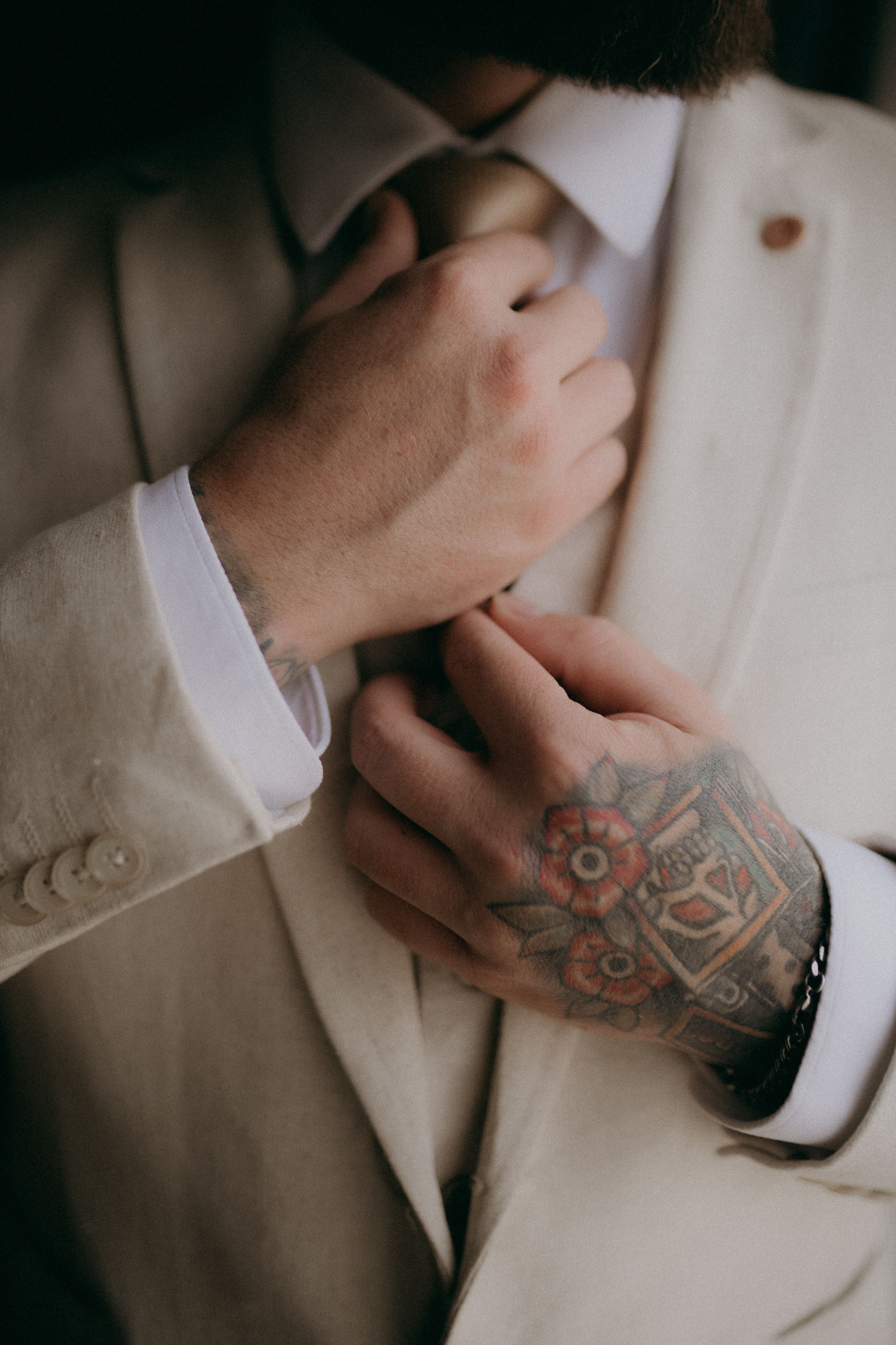 Homem de terno com tatuagem old school visível na mão